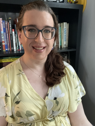 Self portrait at home in front of bookshelf.